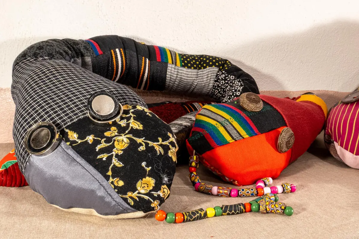 Serpents décoratifs en patchwork de tissus gris, noir et rouge, aux yeux en boutons